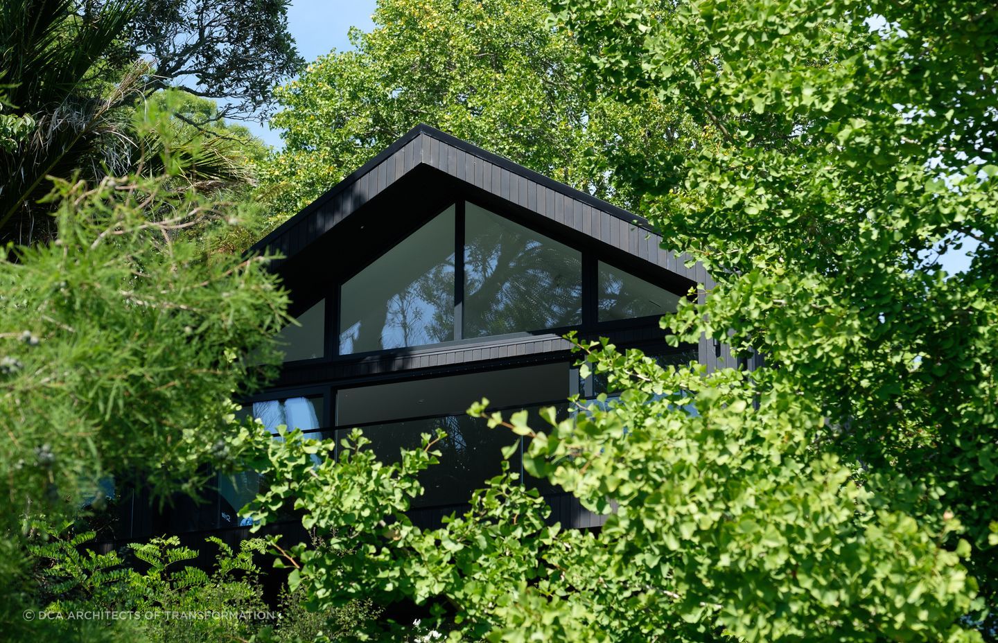 The gabled roof profile peaks out among lush surroundings.