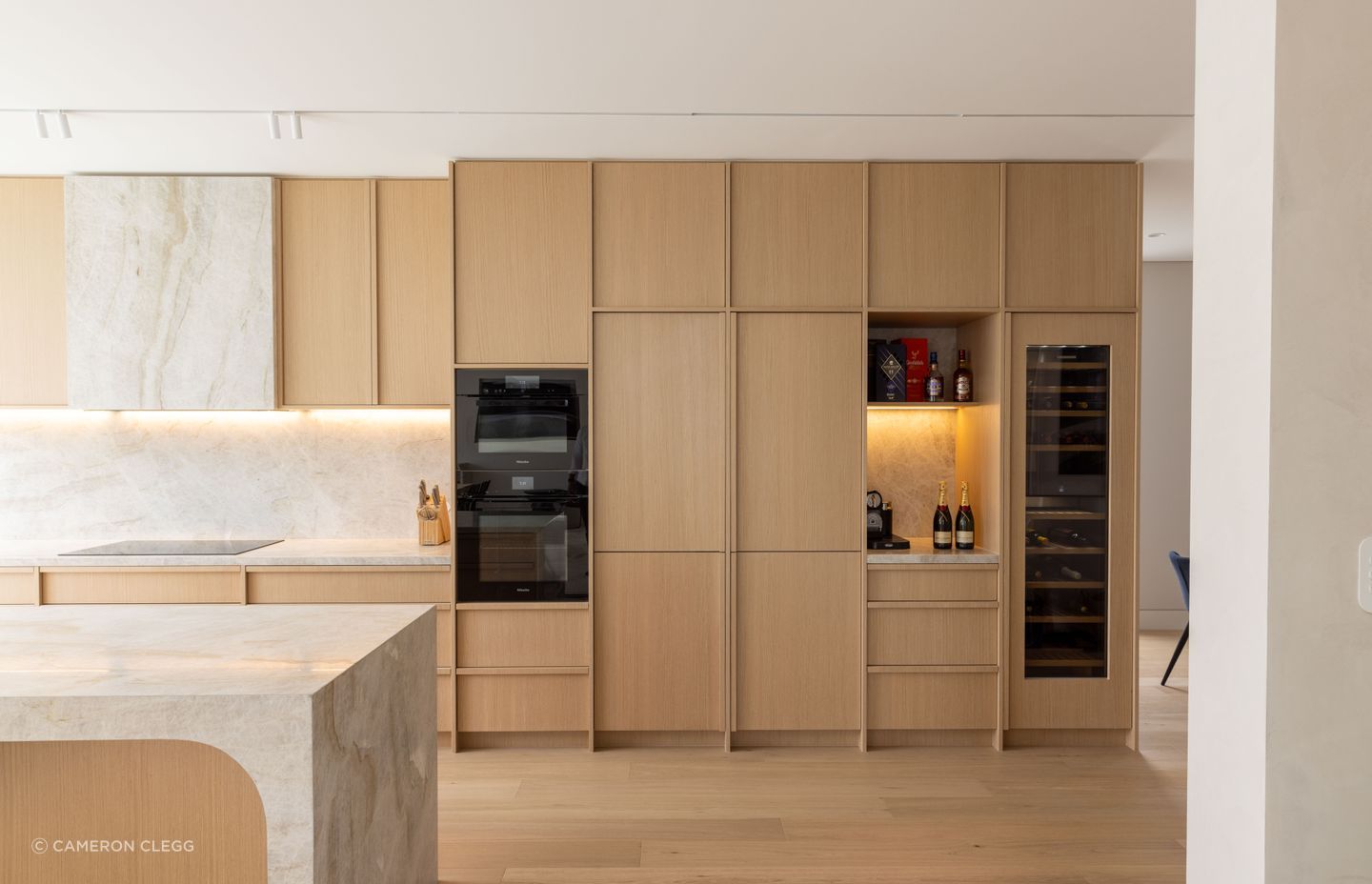 Natural timber and stone come together in the kitchen, with curved detailing in the island bench.