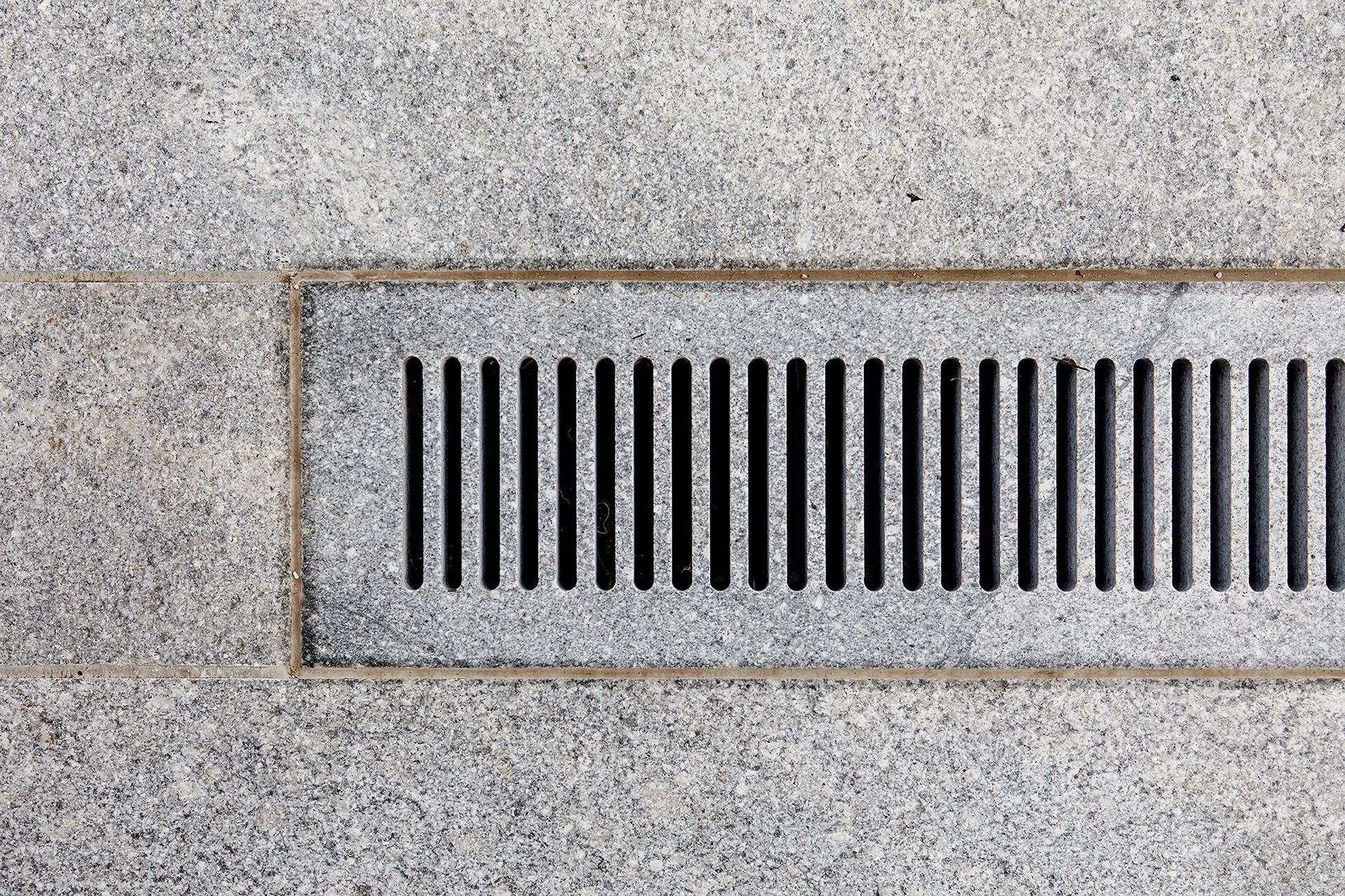 A stone grate runs along the pool's length as the primary drainage point.