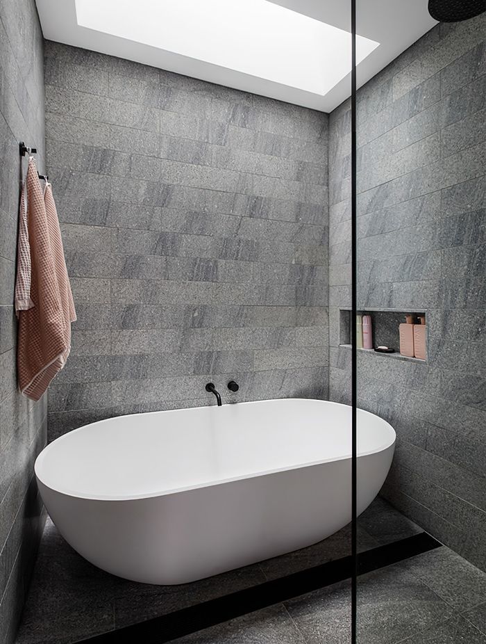 Aston grey granite tile surrounds the luxury white freestanding bath.