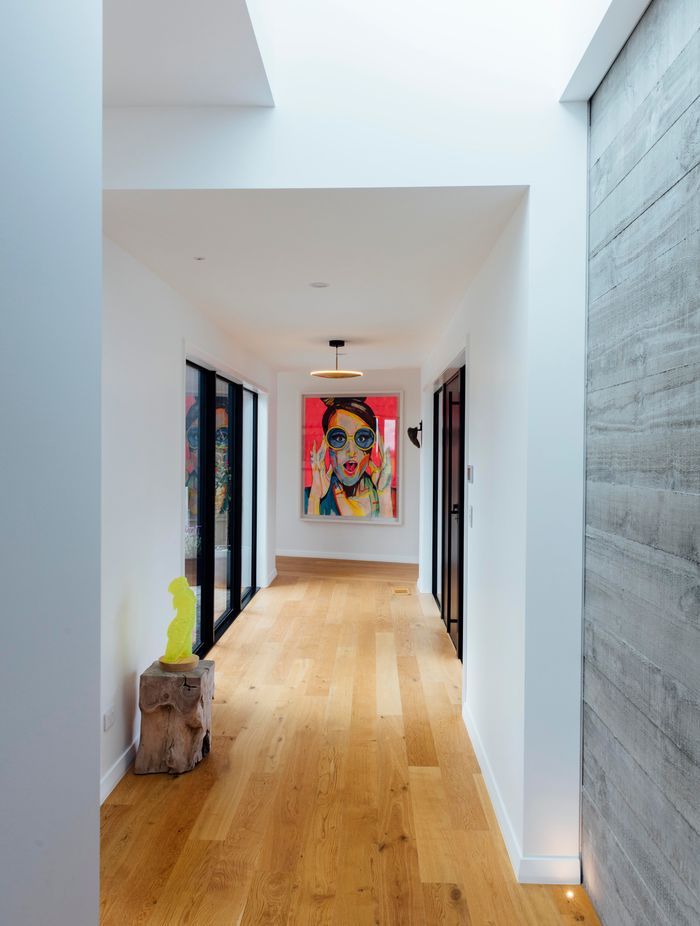 The long run of hallway, with concrete tilt panels on display and an artwork by the homeowners. Afternoon light enters through the skylights and washes down the walls, says Brendon.