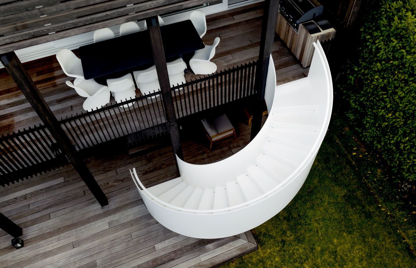 The dramatic white spiral stair contrasts against the darker exterior elements.