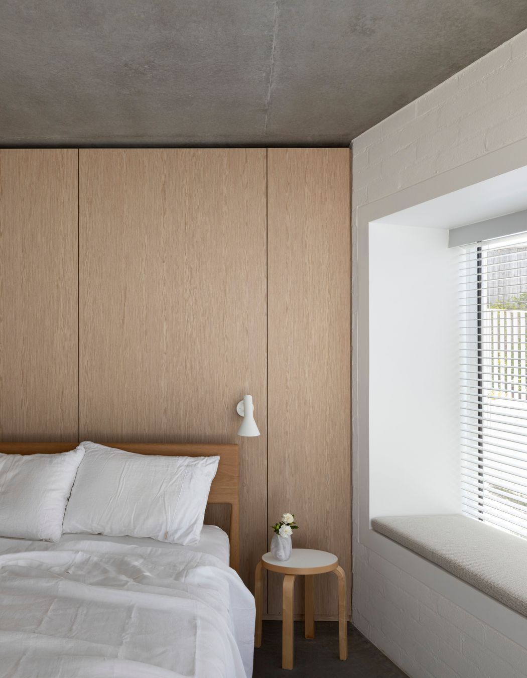 Simplicity of materiality creates a restful bedroom space with timber, concrete and white bagged brick.