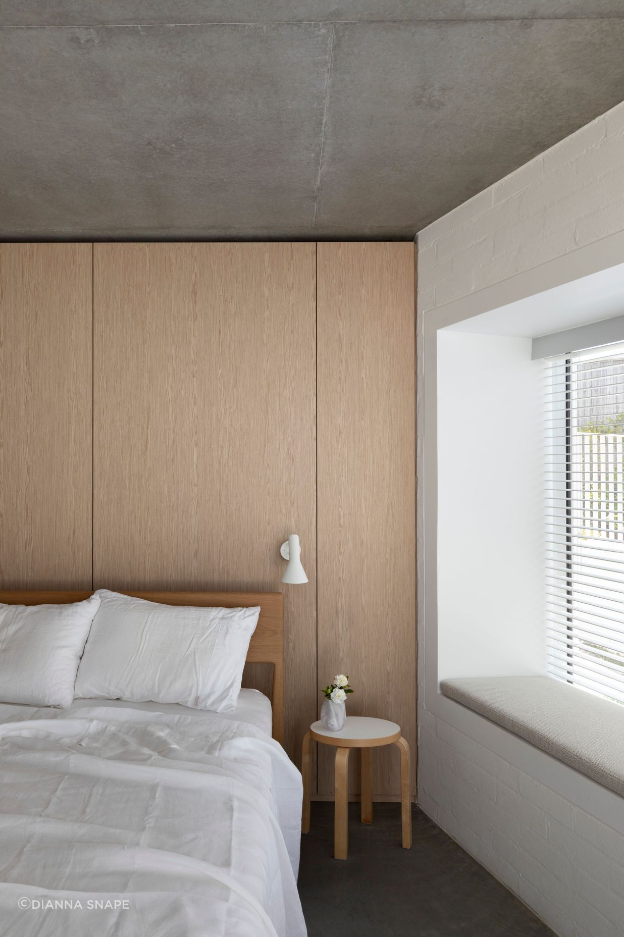 Simplicity of materiality creates a restful bedroom space with timber, concrete and white bagged brick.