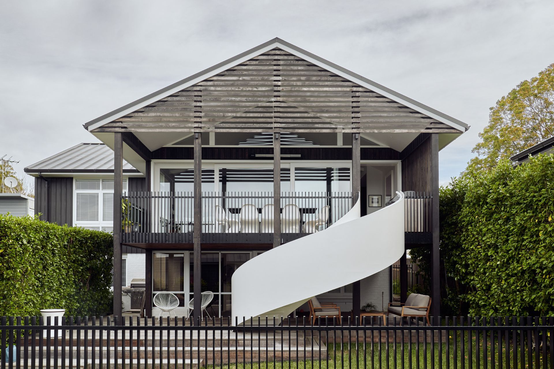 The exterior was completely revamped, a deck added, and a sculptural spiral stair connects the living spaces with the pool.