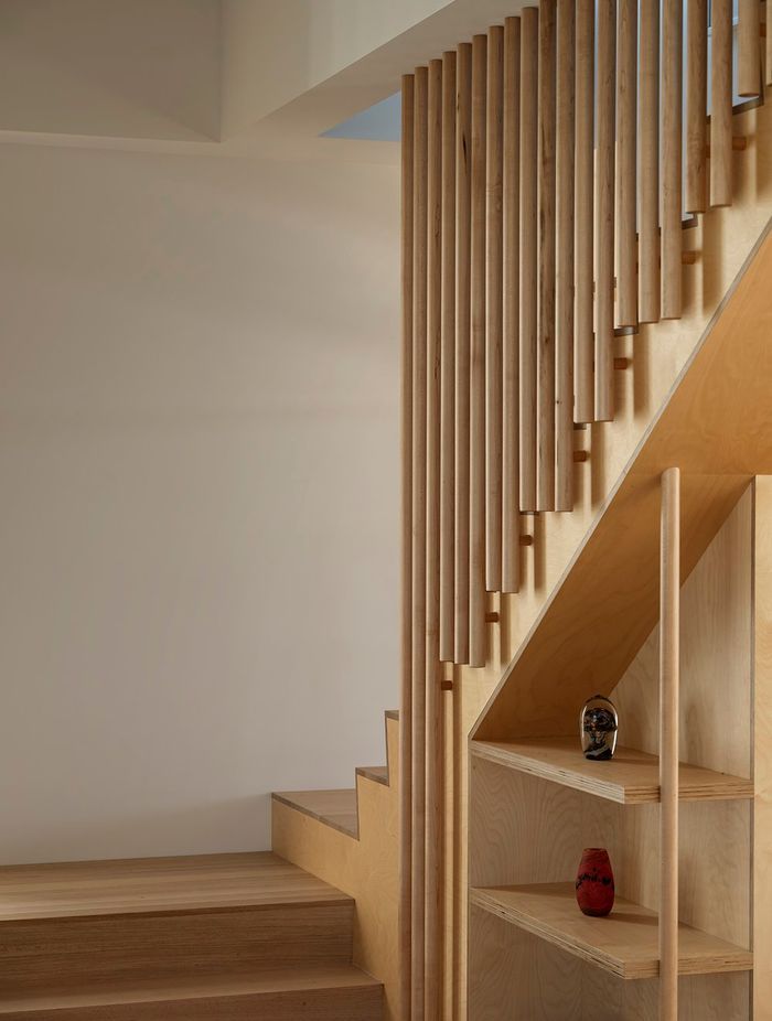 An open staircase leads up towards a second bedroom, bathroom, and multi-purpose space with a kitchenette.