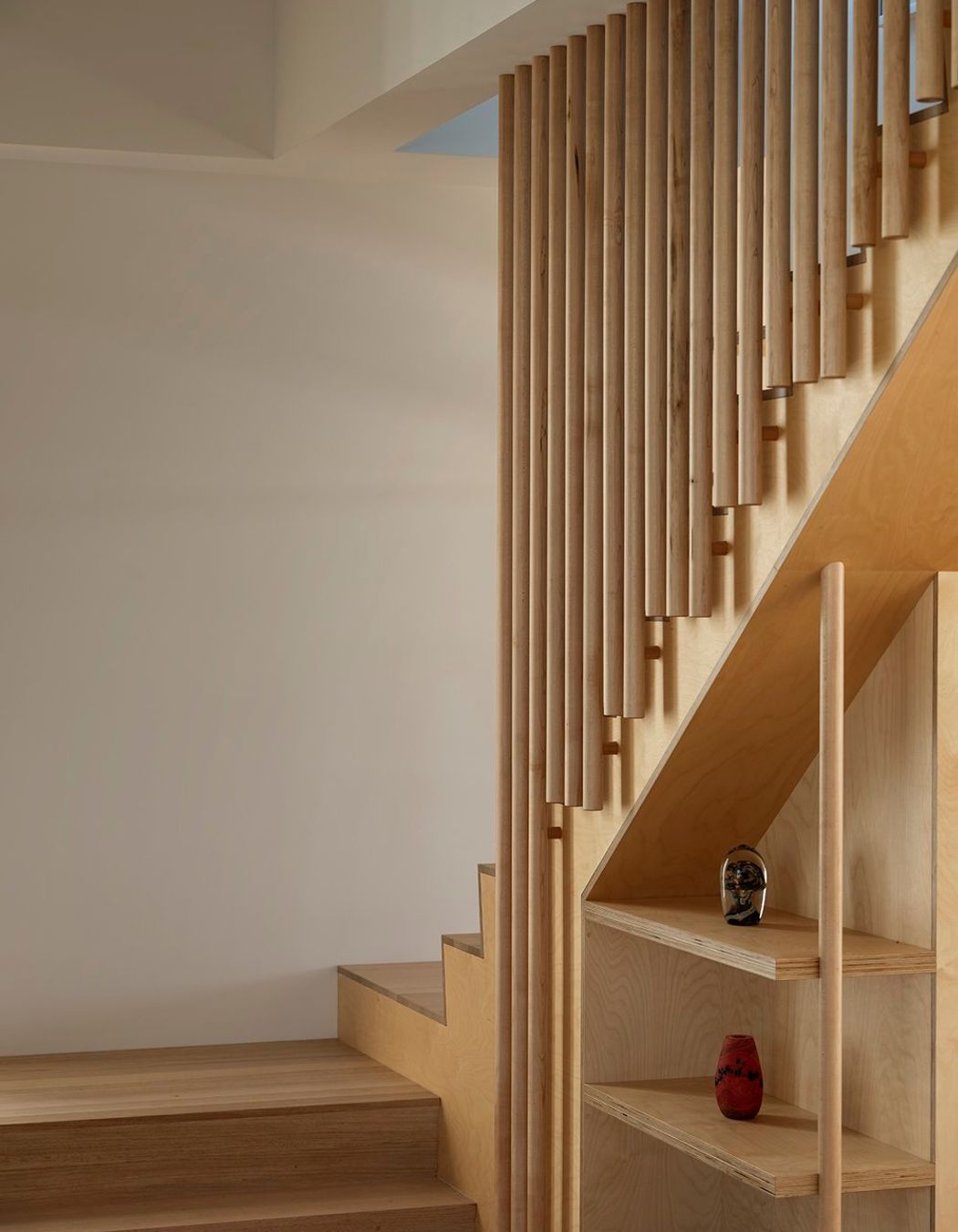 An open staircase leads up towards a second bedroom, bathroom, and multi-purpose space with a kitchenette.