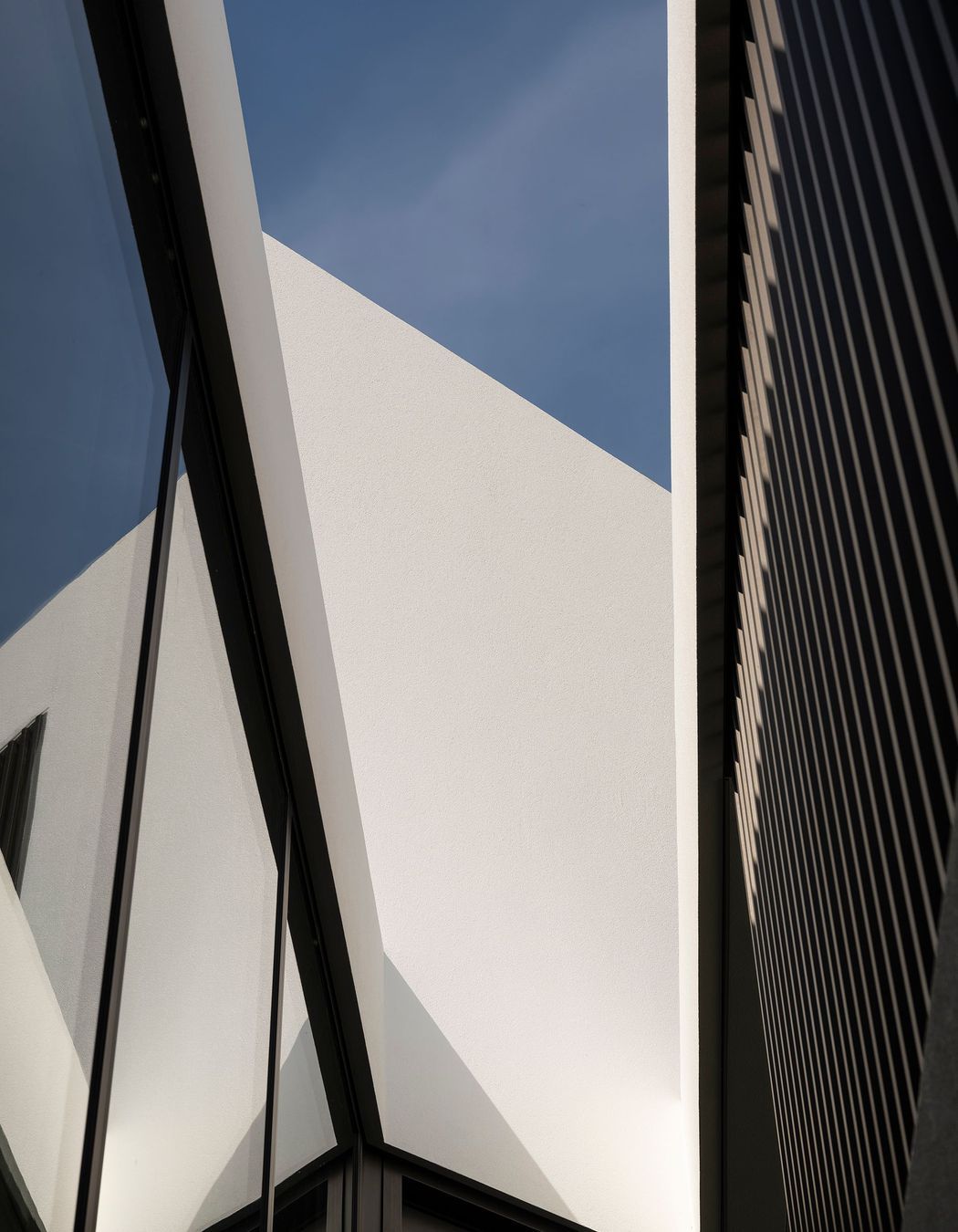 The  shadows from the cedar fins are beautifully reflected by the glass and as shadows on the plaster surfaces, creating a constant play of light and shadow.