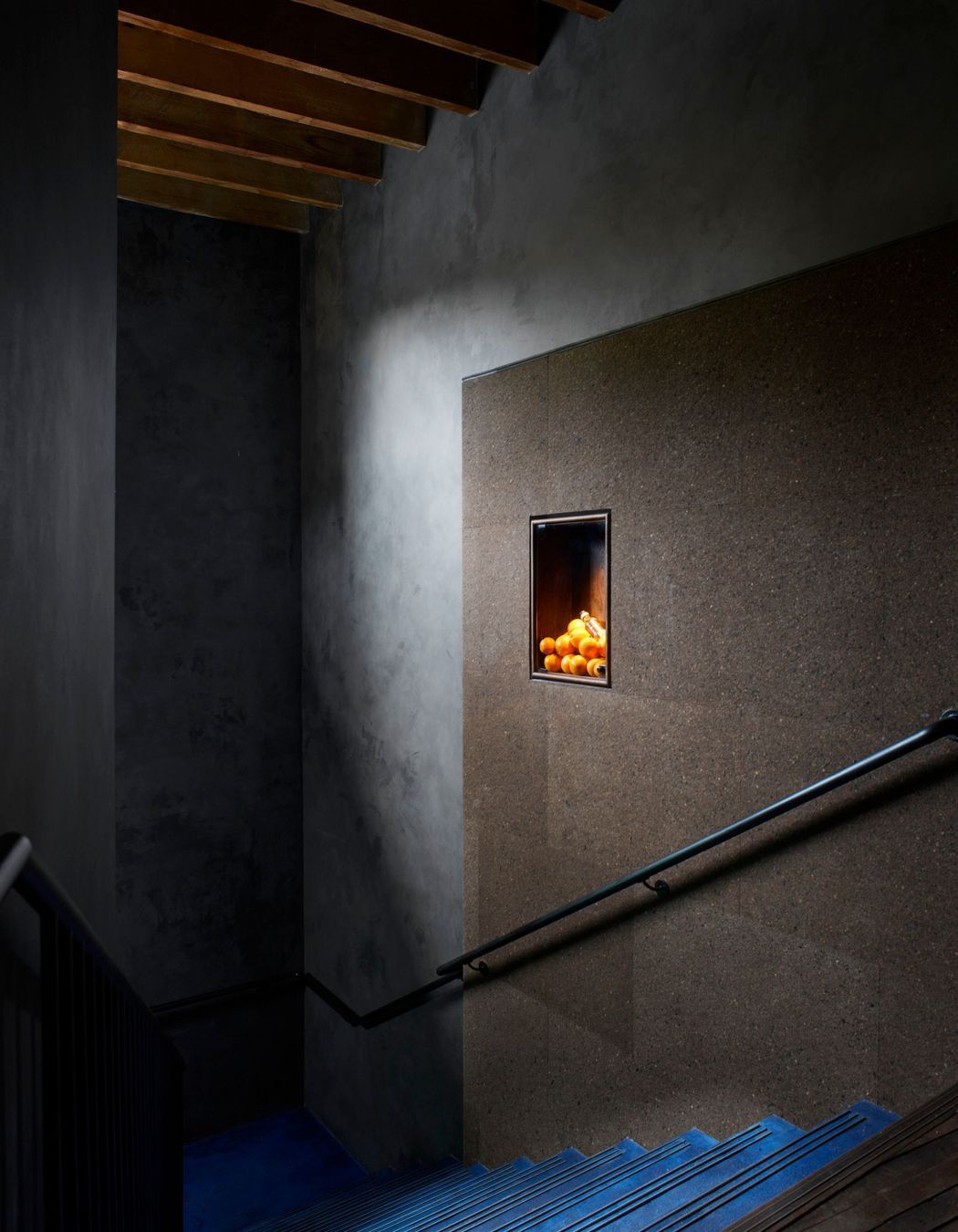 Clad in charcoal Portuguese cork panels, the staircase wall leading to the Gin Lab provides acoustics and internal advertising needs in one, thanks to its pin-able surface.
