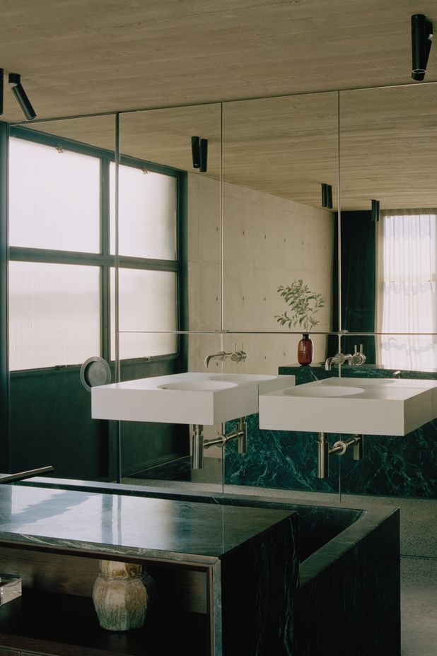 The master en suite features dramatic black marble and a mirrored wall.