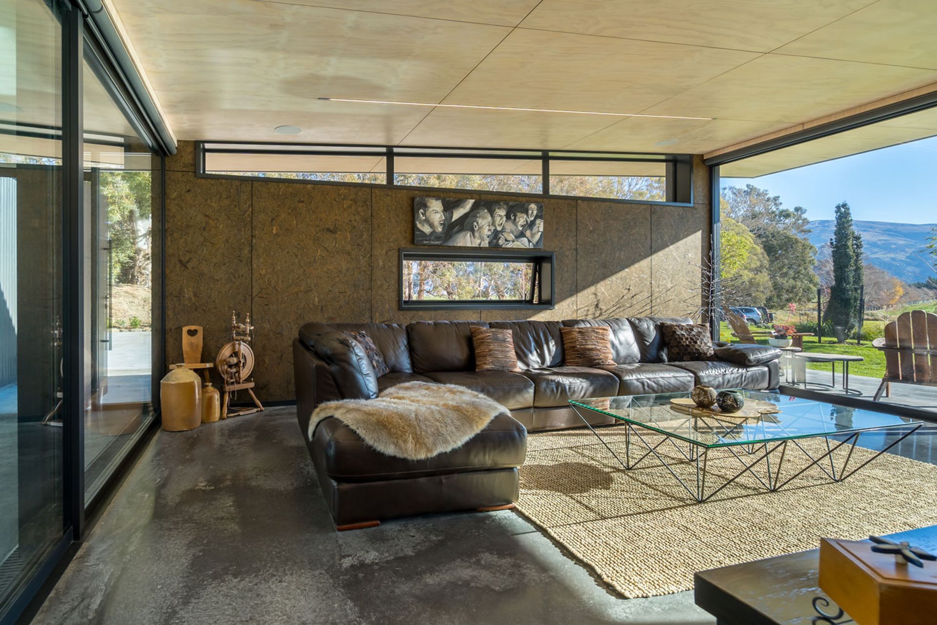 The spinning wheel was Sue’s mother’s, and the painting by a friend depicts the excitement of watching a game. “That’s what goes on in our lounge,” says Sue. The textured wall is strandboard, which blends with the landscape.