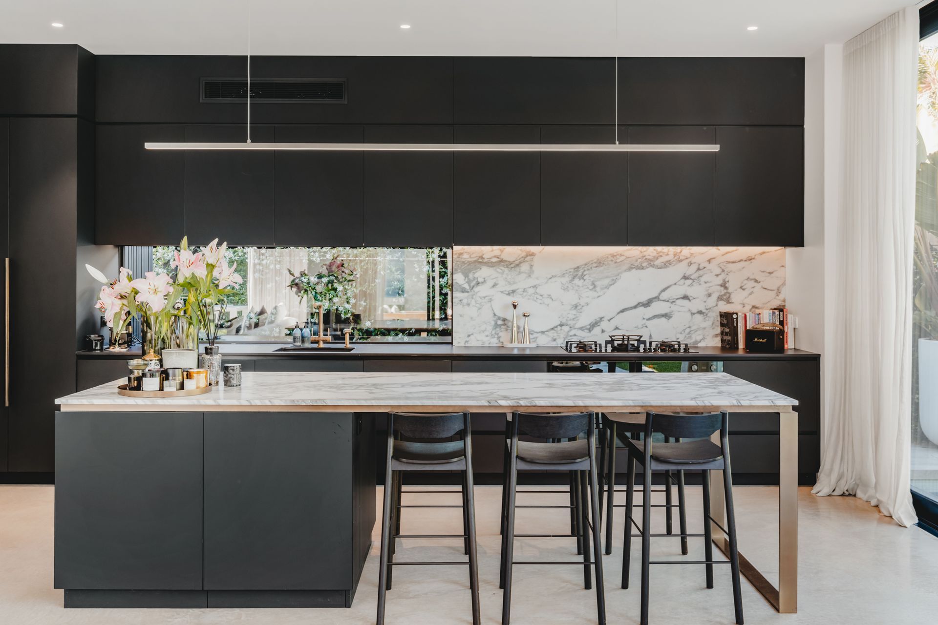The dramatic kitchen combines traditional marble with dark cabinetry.
