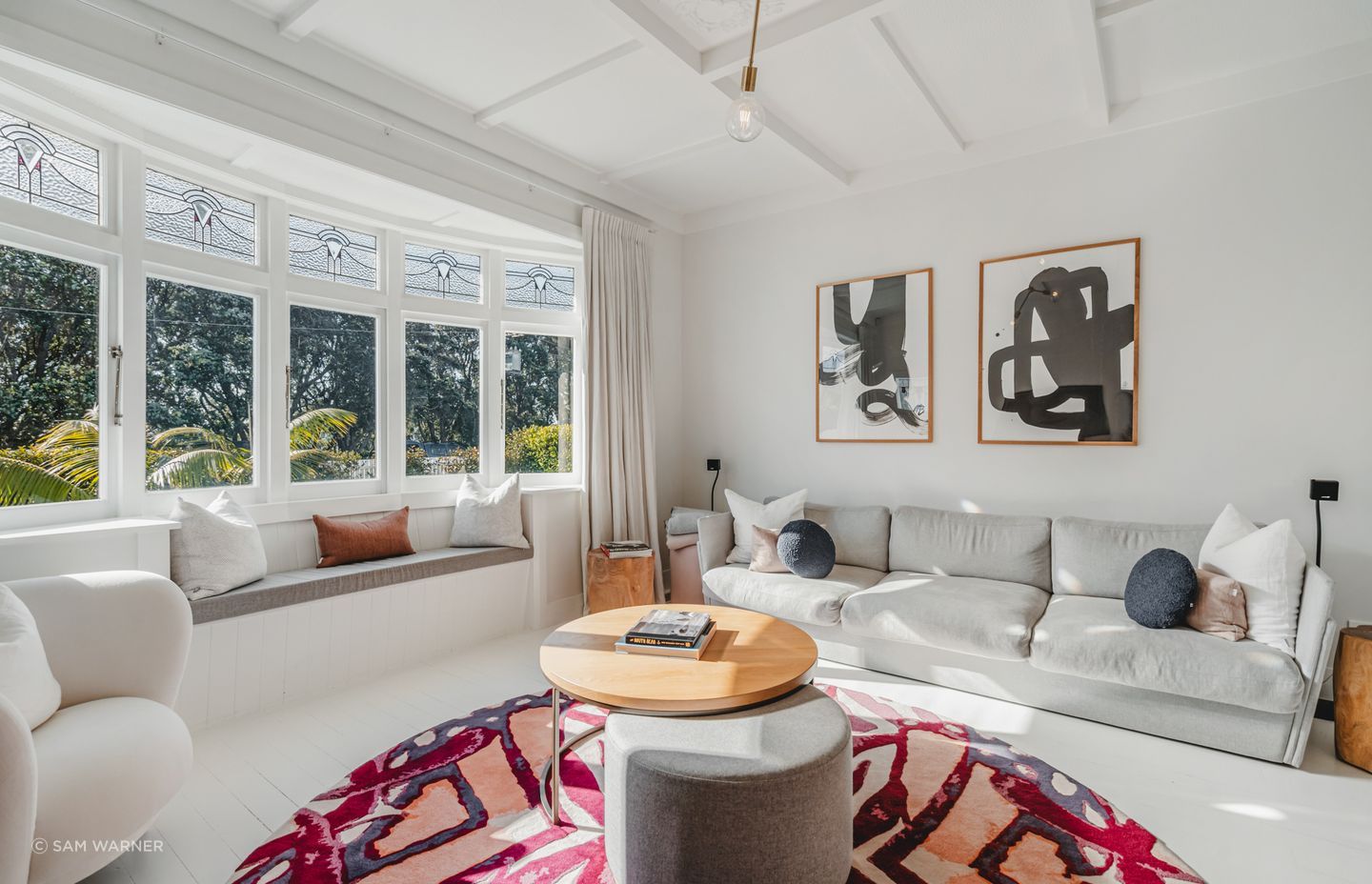 The original bay window at the front of the house was retained, and the white space is elevated with a bold rug and artwork.