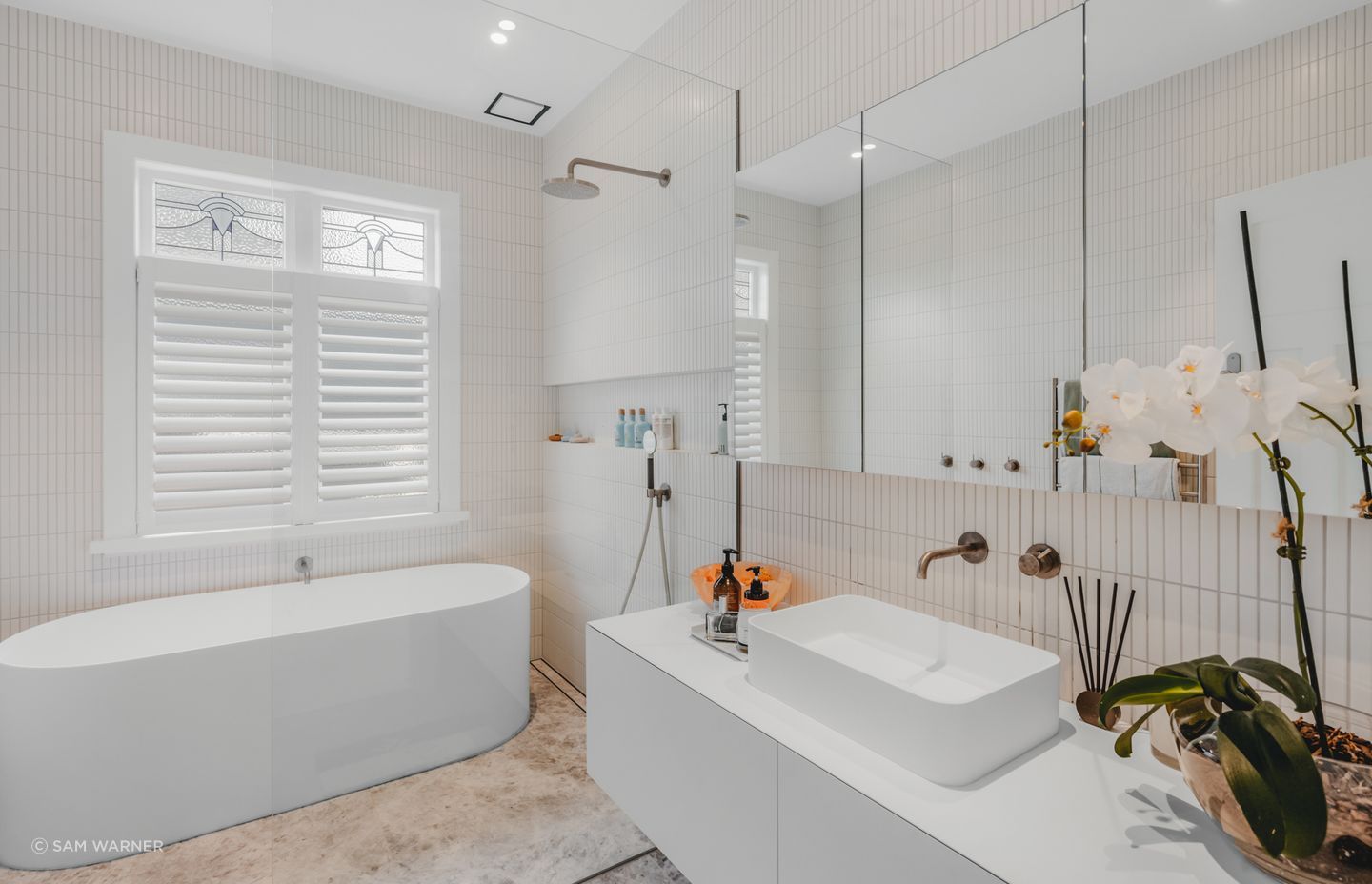 The family bathroom embraces a low-contrast look, with a large white type and pale, floor-to-ceiling tiles.