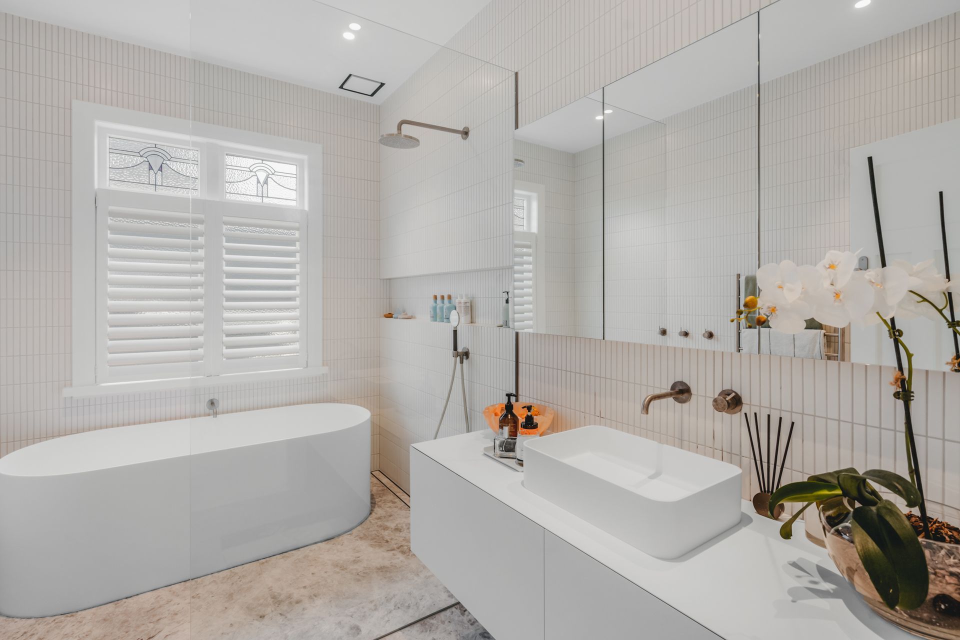 The family bathroom embraces a low-contrast look, with a large white type and pale, floor-to-ceiling tiles.