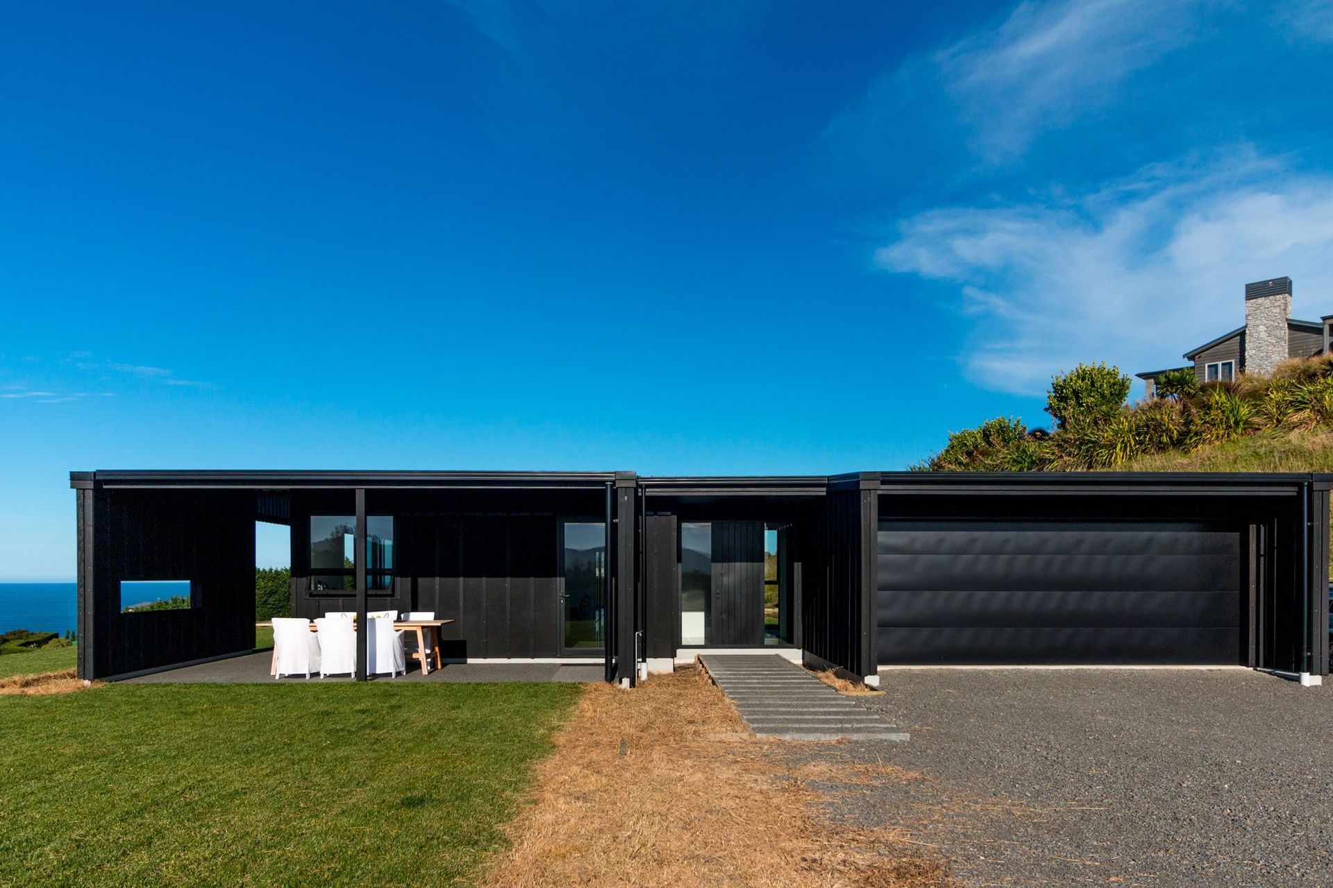 The bold, black cladding of the barn-style home on Heipipi Drive contrasts dramatically against the clear blue sky.