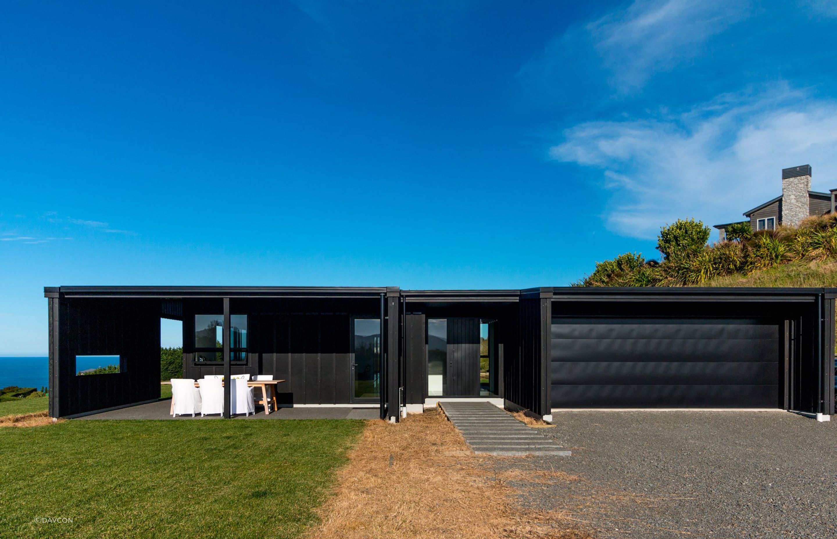 The bold, black cladding of the barn-style home on Heipipi Drive contrasts dramatically against the clear blue sky.