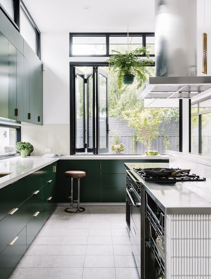 The kitchen island workspace is stainless steel with custom steel rack draws providing easy access to pots and pans. The rest of the joinery is 2pac dark green with a Dekton glacier benchtop.