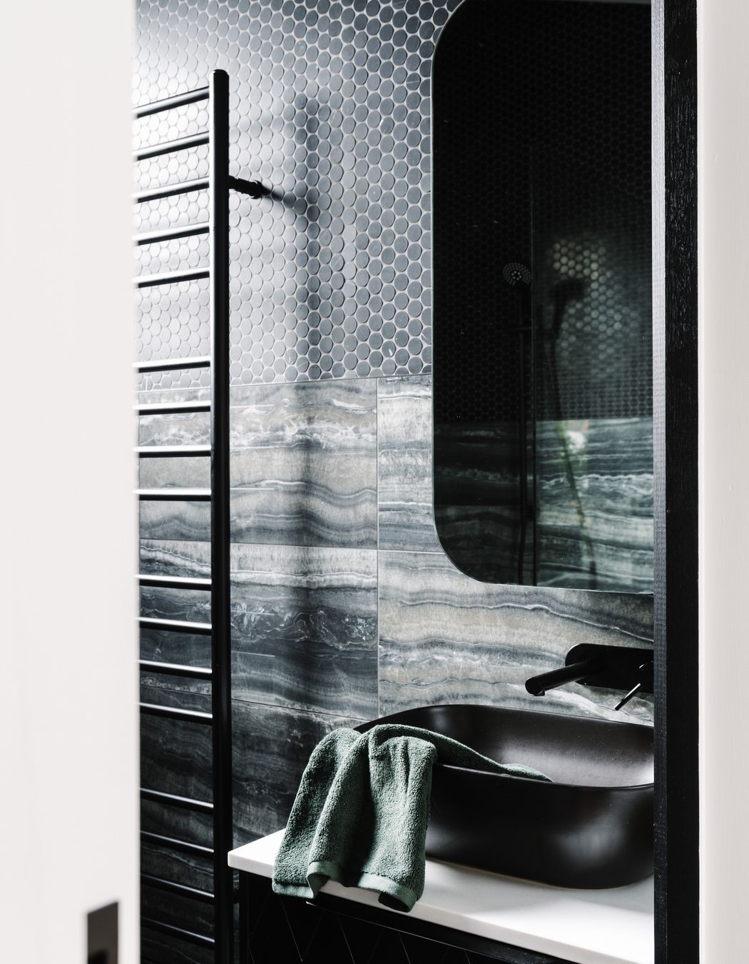 The master ensuite is a contrast to the main bathroom with its dark, masculine colour palette.