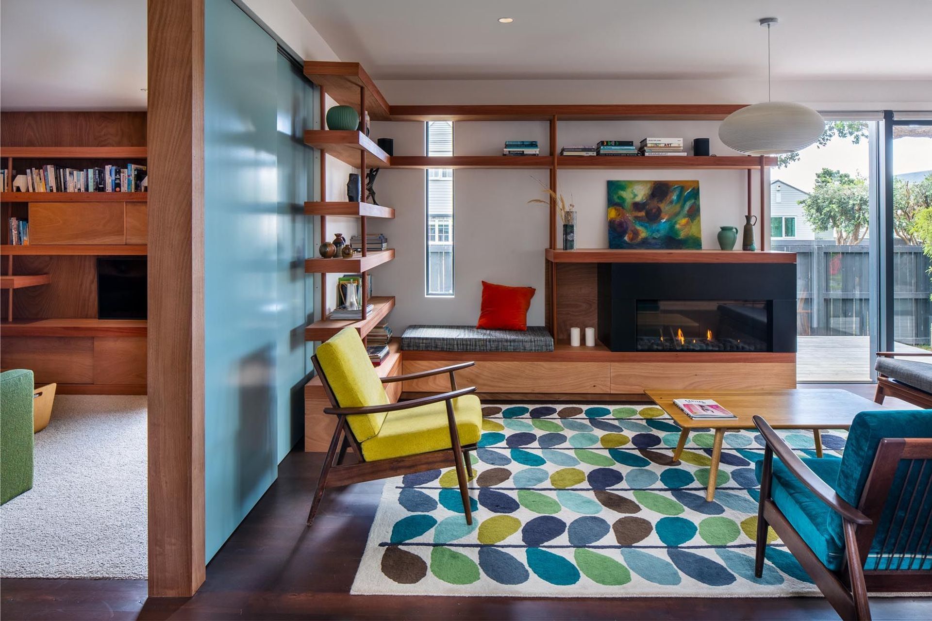The built-in window seat is one of many options in the house for a sunny spot to sit. Sturdy timber shelving adds weight to the room, and the clients helped choose the mid-century furnishings.