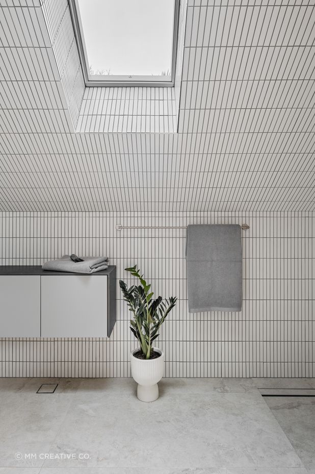 The upstairs bathroom is light and airy, featuring white finger tiles and skylights.