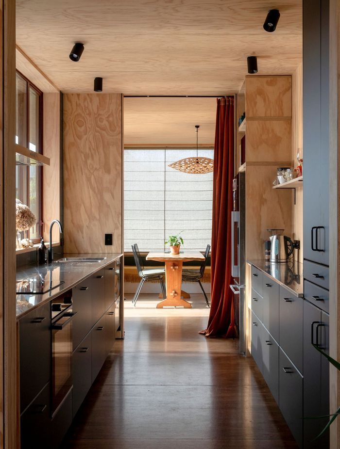 The galley-style kitchen with living areas at both ends. The pendant light is Flax by David Trubridge, and the flooring is Meranti plywood.