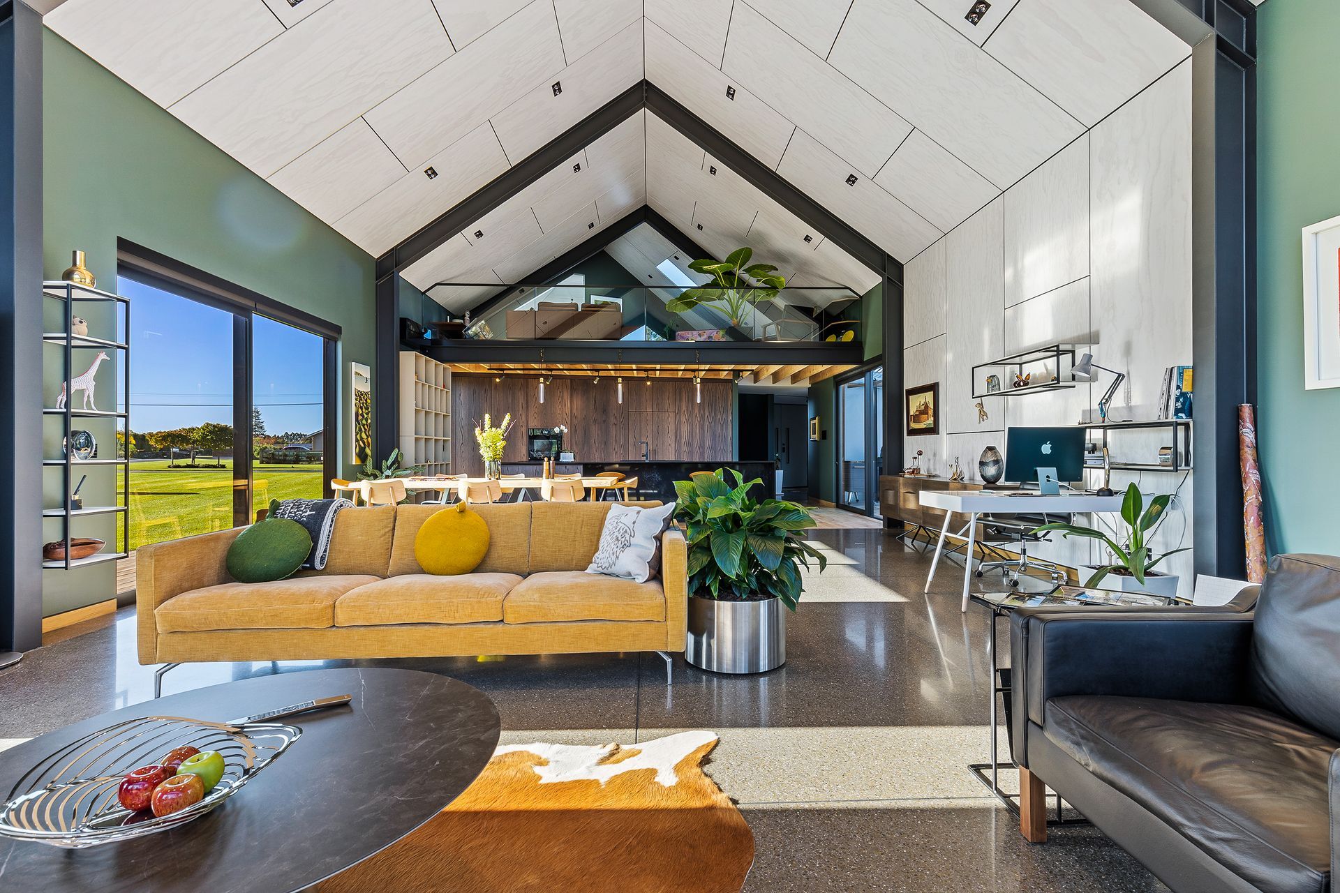 The plywood ceiling with shadow detailing extends down a section of wall in the open-plan dining and living area.