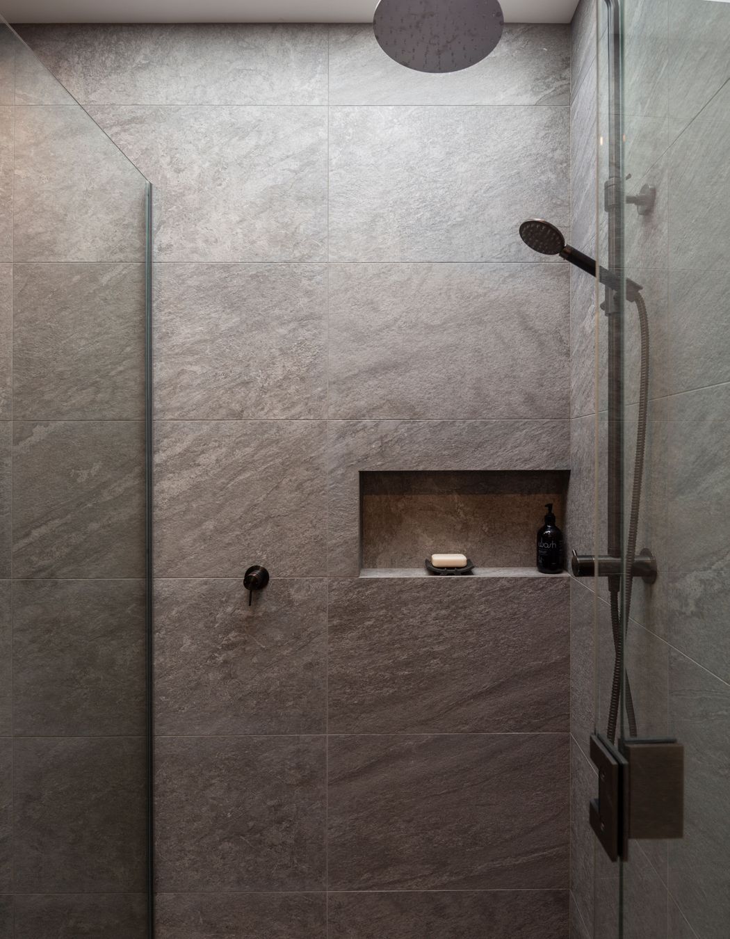 The fully tiled guest shower drinks in the light from an overhead aperture.