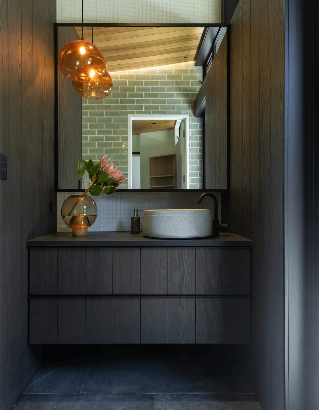 The master room’s ensuite, designed with custom cabinetry, handmade tiles, and a feature pendant light that hangs in counterbalance to the clerestory windows.