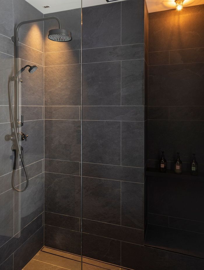 Black textured tile in the bathrooms contrasts with white board and batten that is used in the hallways.