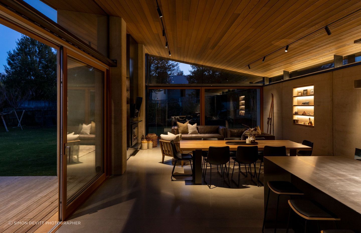 The main living area, sheltered by one sweeping cedar ceiling that extends to an external overhang. | Photographer: Simon Devitt