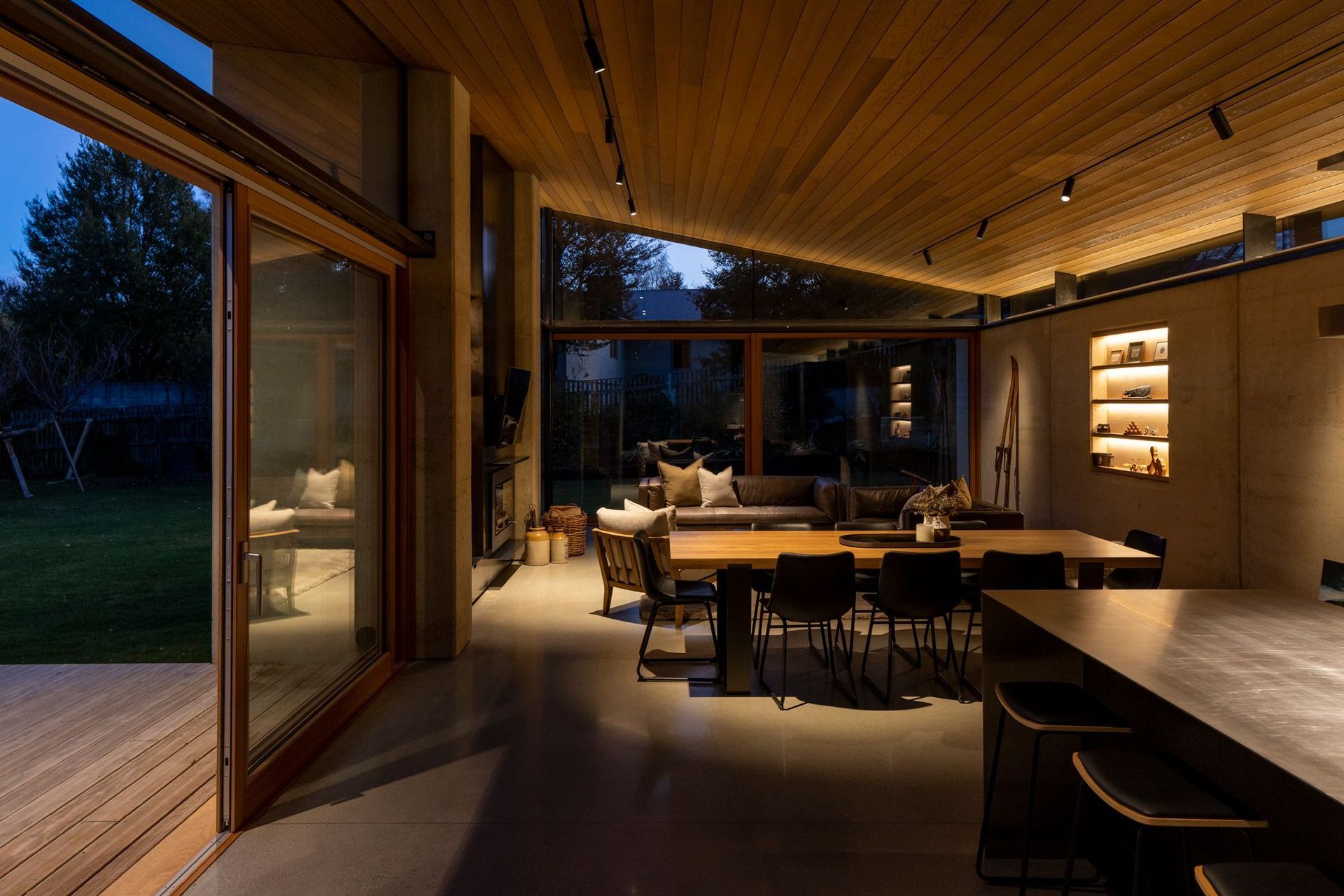 The main living area, sheltered by one sweeping cedar ceiling that extends to an external overhang. | Photographer: Simon Devitt