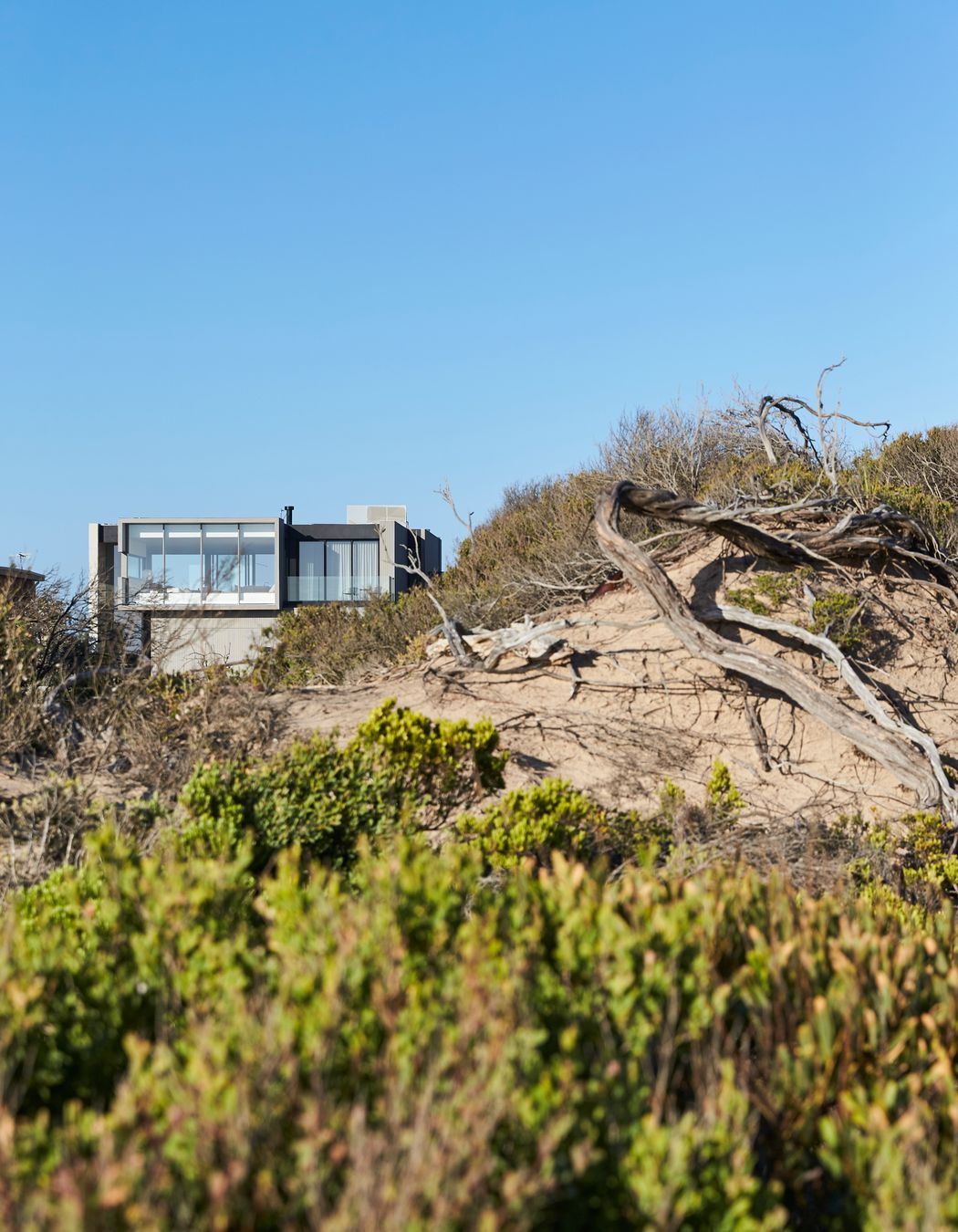 The concrete form of the home integrates into the beach setting.