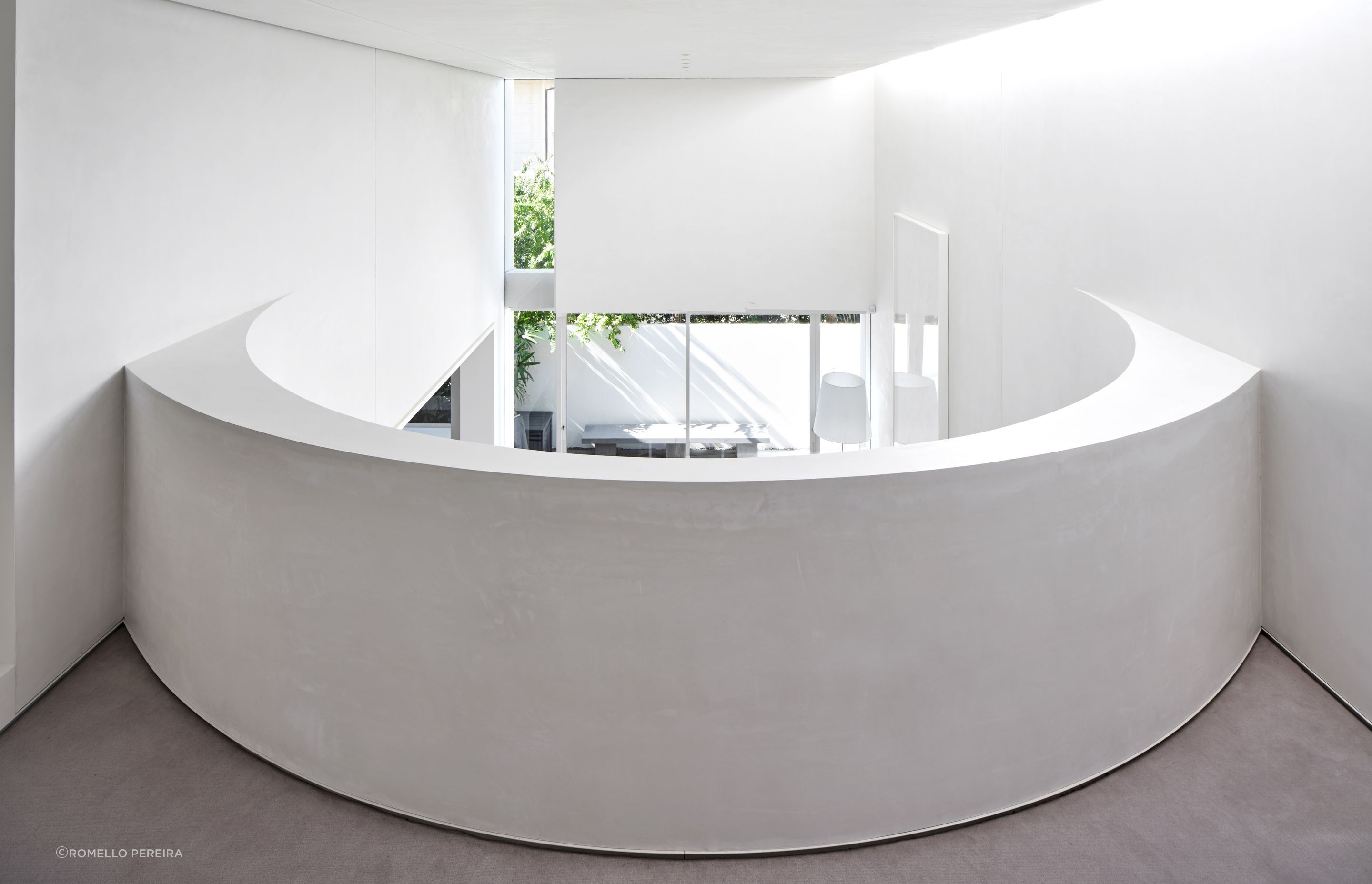 The curved wall of the mezzanine, looking down over the living and outdoor spaces.