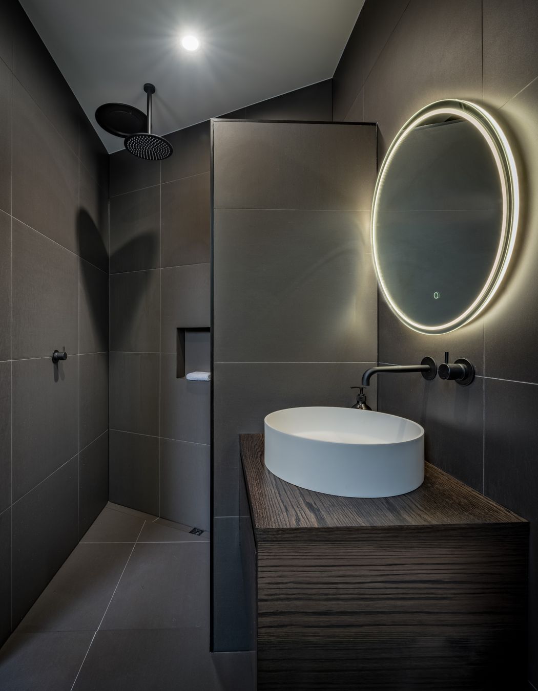 A guest bathroom and bedroom were decided on late in the design and were tucked in behind the angled garage. “That  created an interesting shape and the shower shows that.”