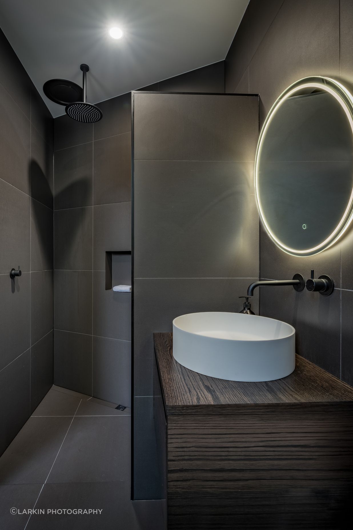 A guest bathroom and bedroom were decided on late in the design and were tucked in behind the angled garage. “That  created an interesting shape and the shower shows that.”