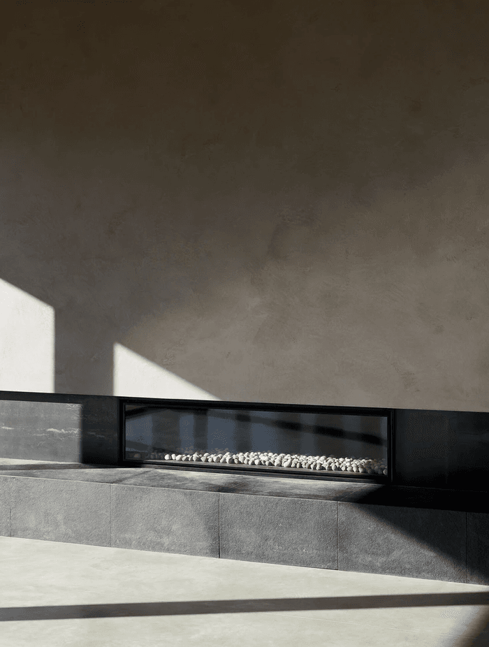 The entrance leads into the centre of the home, opening into an open-plan kitchen, living, and dining space with an oversized fireplace.