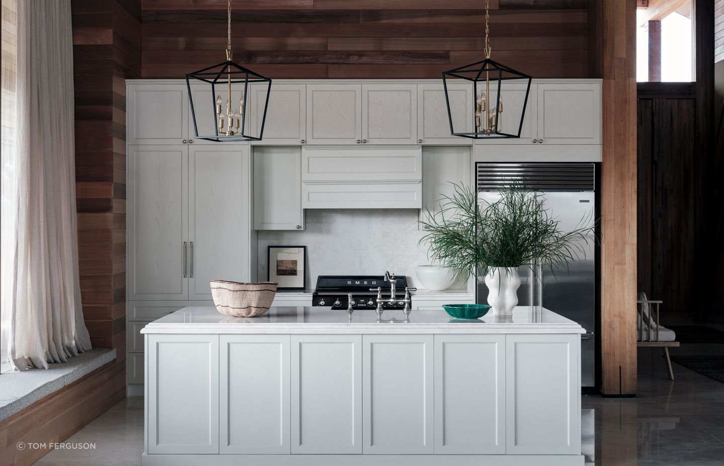 A contrast to the cedar, the kitchen cabinetry is solid oak, hand-painted in white. The orientation of the island bench allows those preparing dinner to look out over the space and still be involved in conversation.
