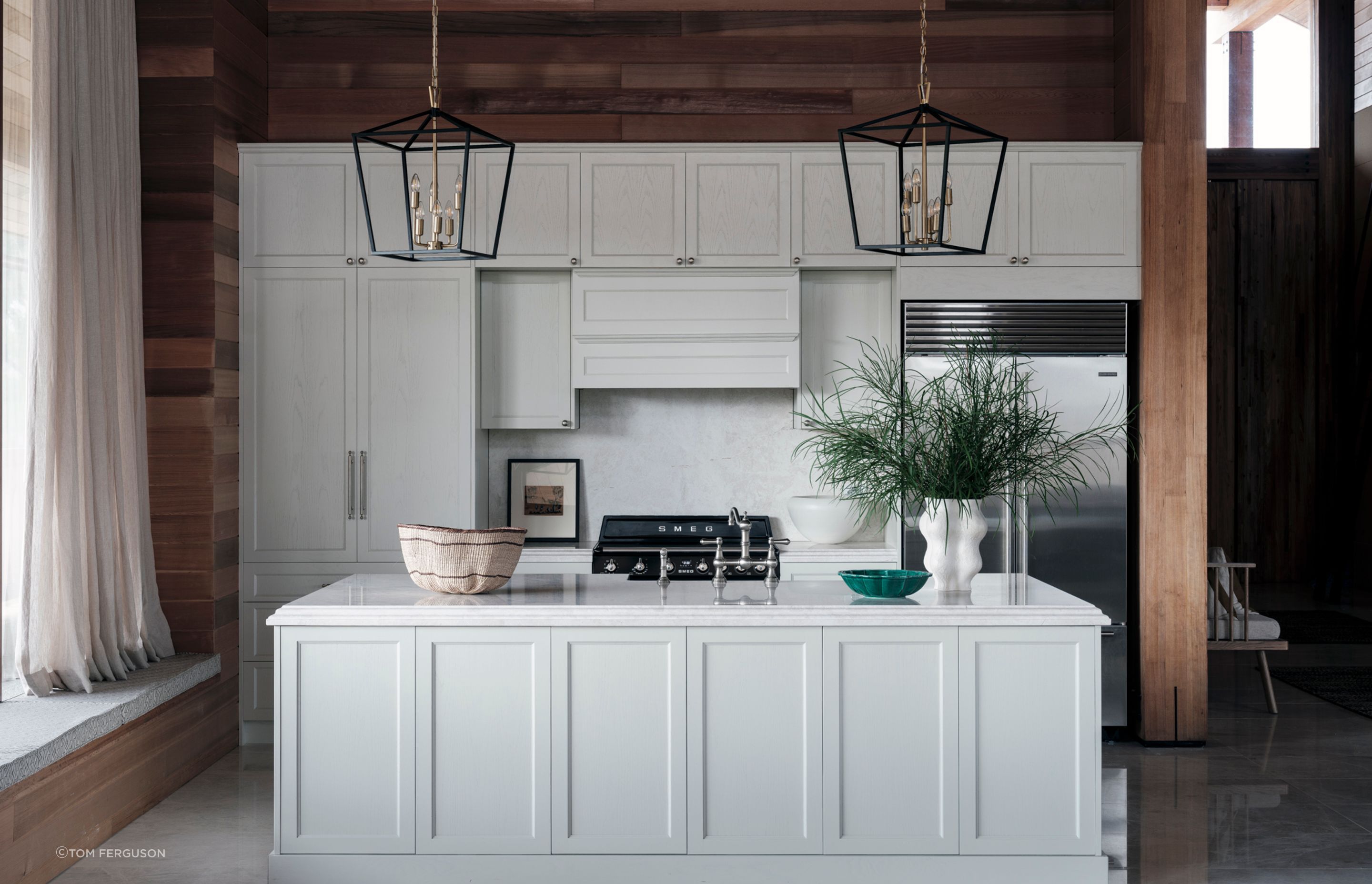 A contrast to the cedar, the kitchen cabinetry is solid oak, hand-painted in white. The orientation of the island bench allows those preparing dinner to look out over the space and still be involved in conversation.