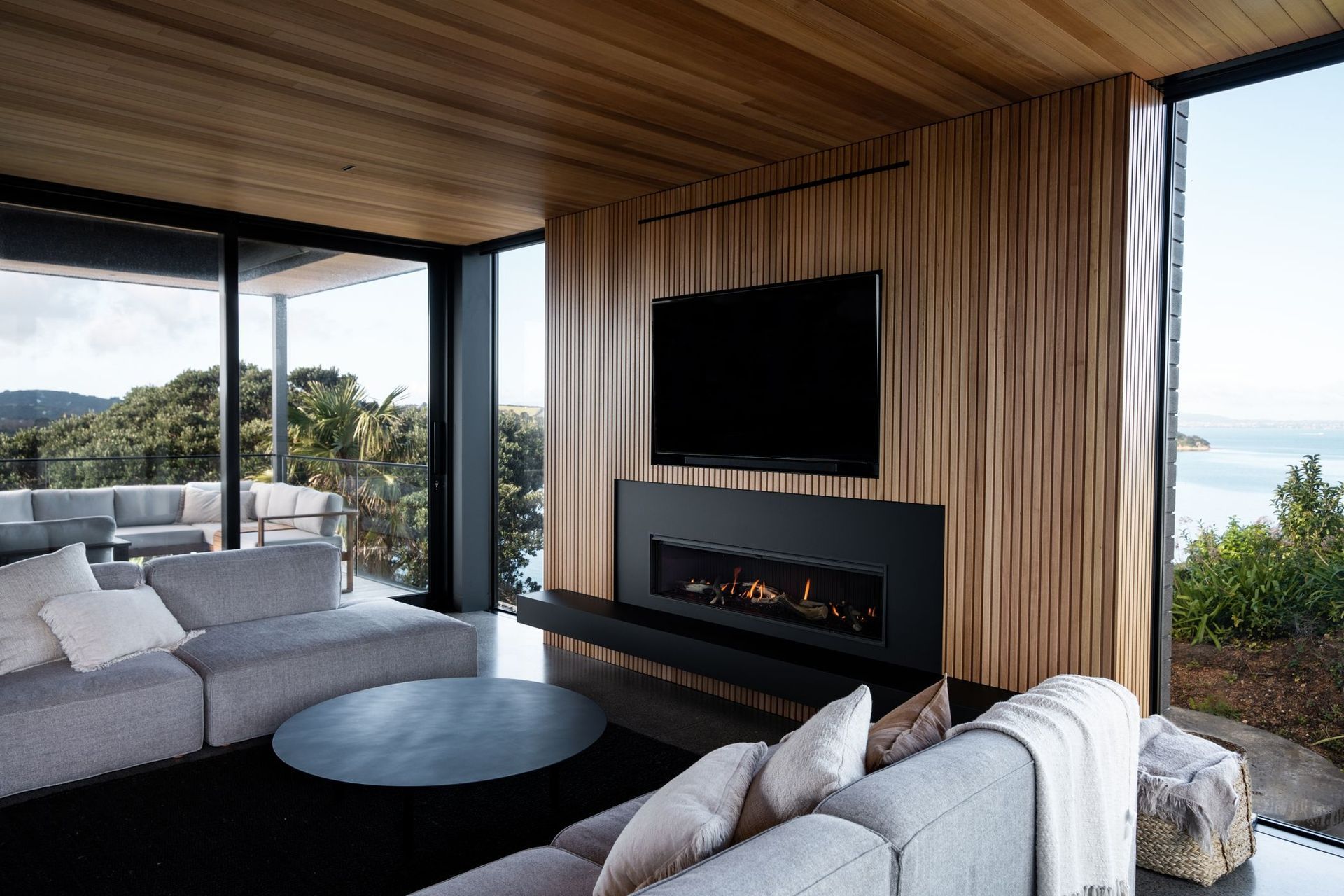 The living area centres around the elegant fireplace, sophistically surrounded by matte-black Fenix and oak paneling.