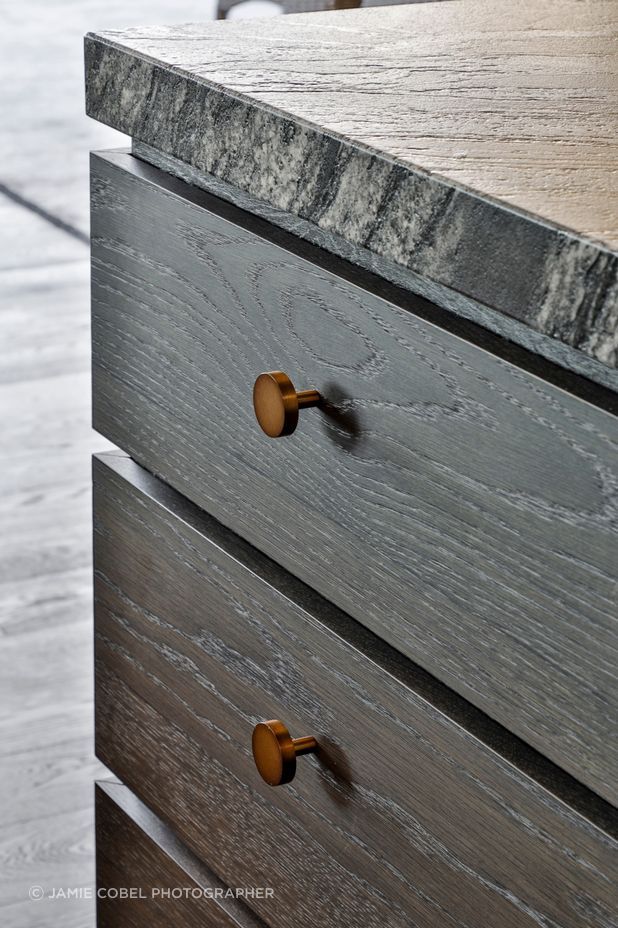 Textural stone benchtops complement the dark timber cabinetry.