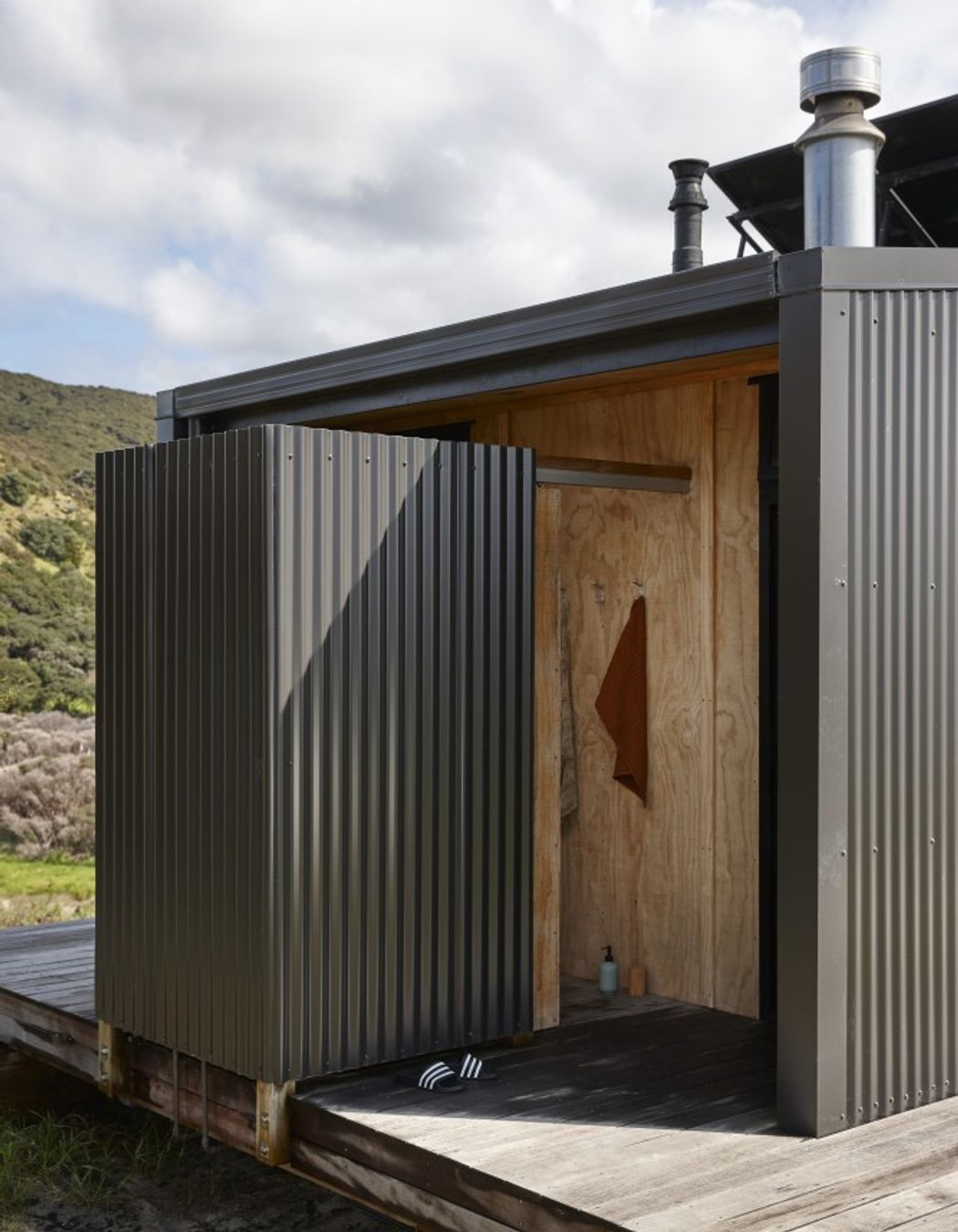 An outdoor shower is formed using corrugated iron and timber.