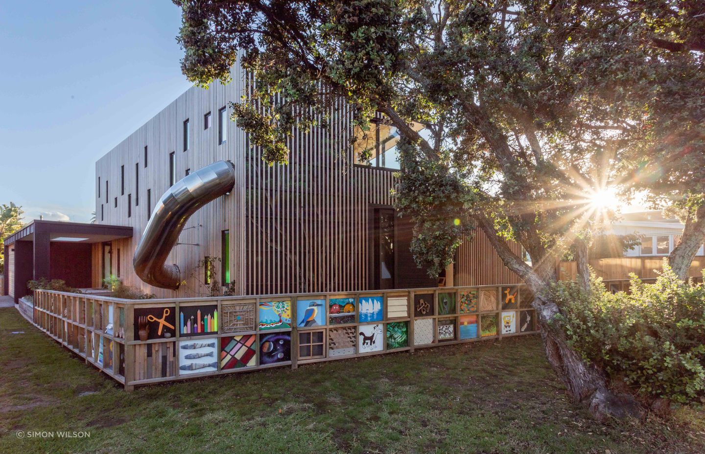 The faint outline of a pōhutukawa mural can be seen beneath the timber batten screen.