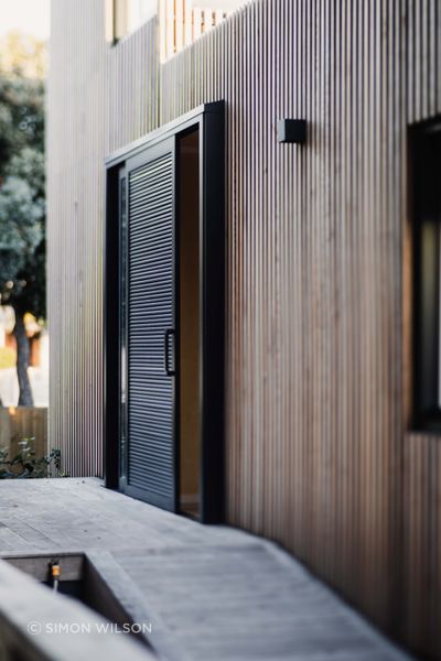 A battened timber screen hugs the painted cladding below.