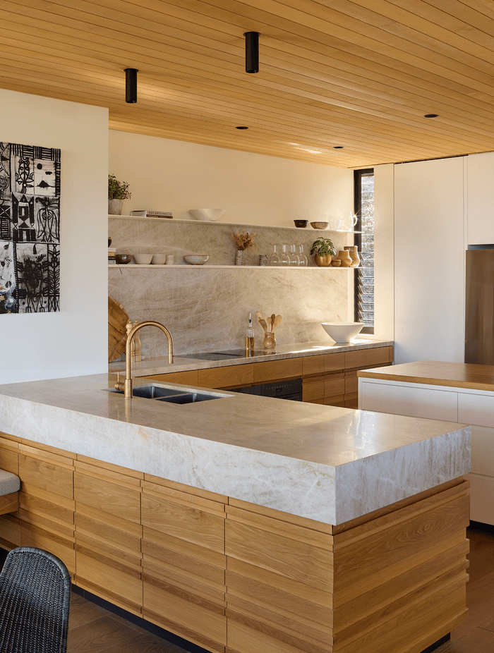 Natural stone complements the timber in the kitchen, which overlooks the dining and lounge areas.
