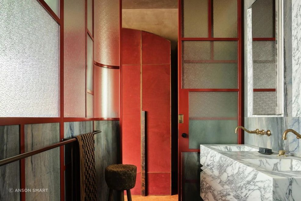 Glazed steel walls and a sliding steel door draw light into The Terrace House bathroom.