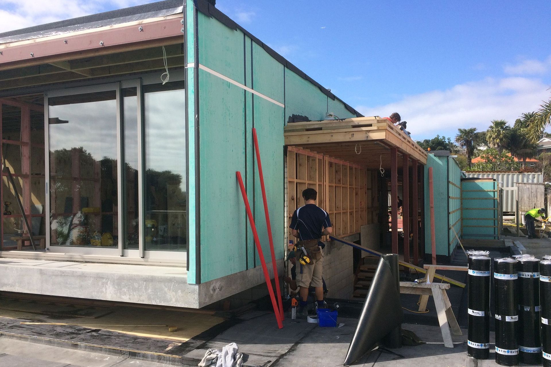 A tradesman installs cladding to the side of the building.