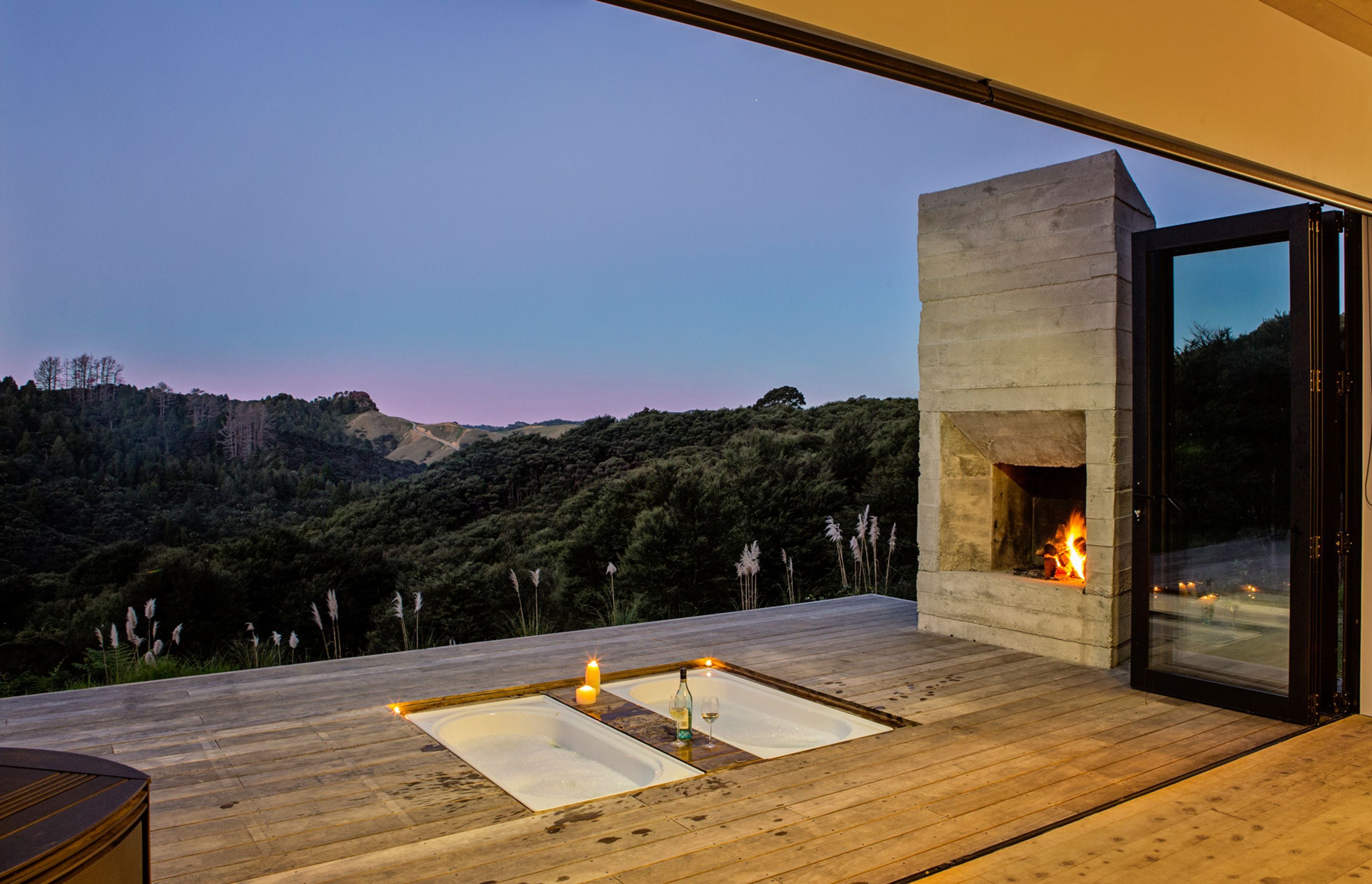 Enjoying bush views and an outdoor fireplace, these twin baths have been inserted into the deck of Back Country House by LTD Architecture and, when not in use, they can also be covered up by a table and chairs. 