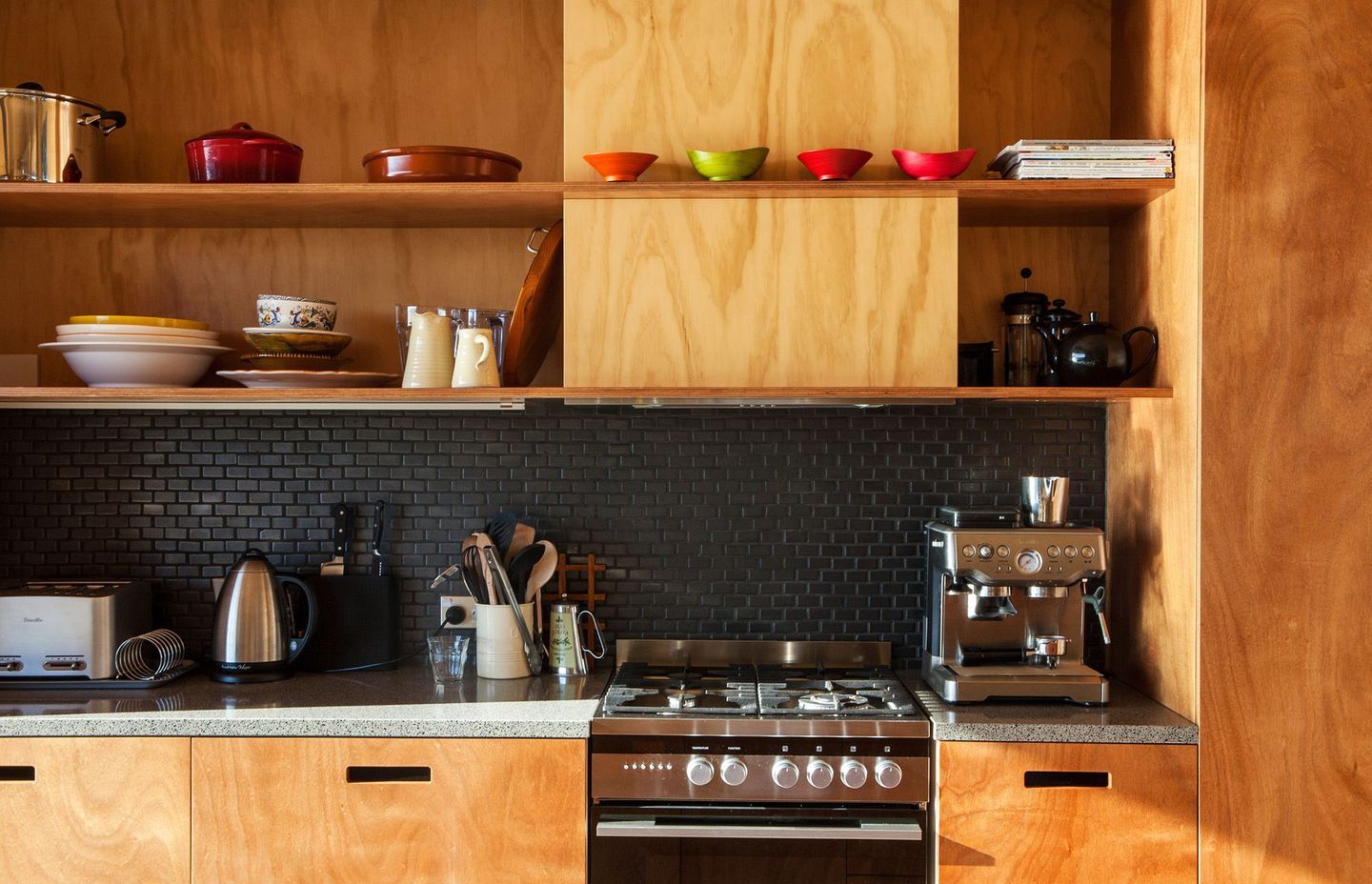 This unique timber-rich kitchen on Great Barrier Island, designed by Green Room Studio, features open shelving.