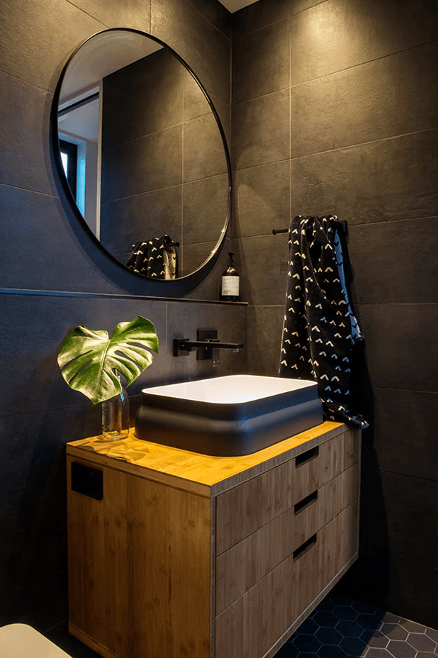 A round mirror, framed in black, is the perfect choice to bounce subtle light around the room while keeping with the theme.